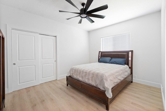 bedroom featuring a textured ceiling, light hardwood / wood-style flooring, ceiling fan, and a closet