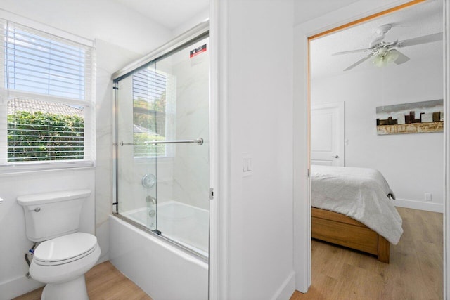 bathroom featuring toilet, wood-type flooring, combined bath / shower with glass door, and ceiling fan