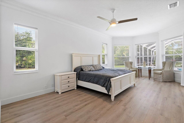 bedroom with light hardwood / wood-style floors, ceiling fan, a textured ceiling, and crown molding