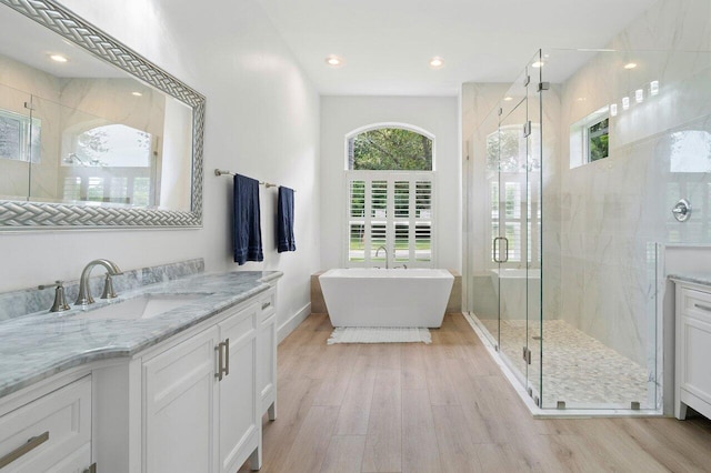 bathroom with hardwood / wood-style flooring, vanity, and shower with separate bathtub