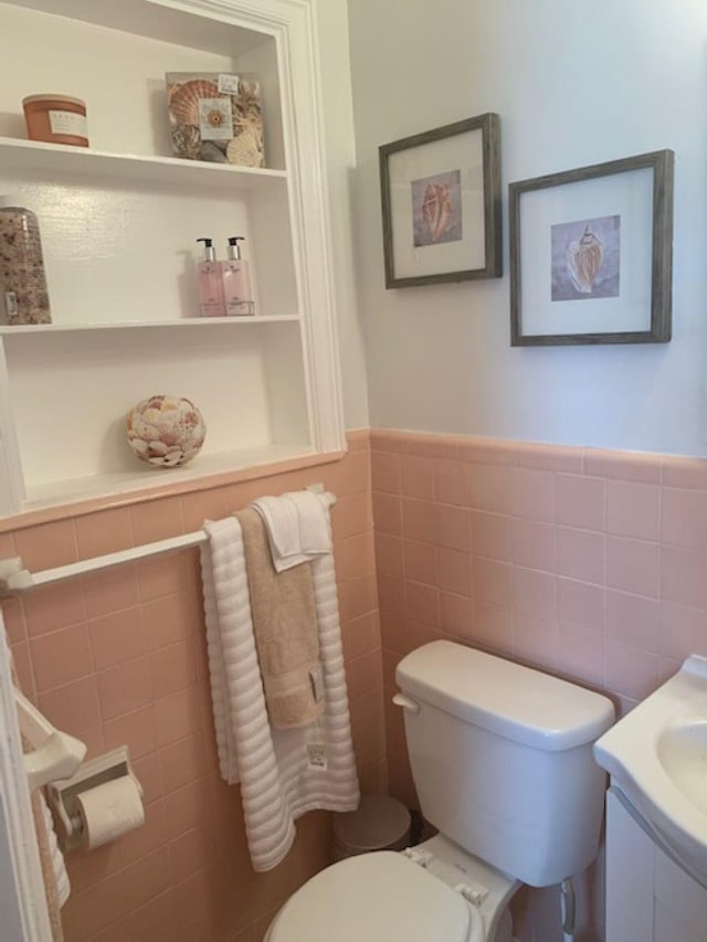 bathroom with toilet, vanity, and tile walls