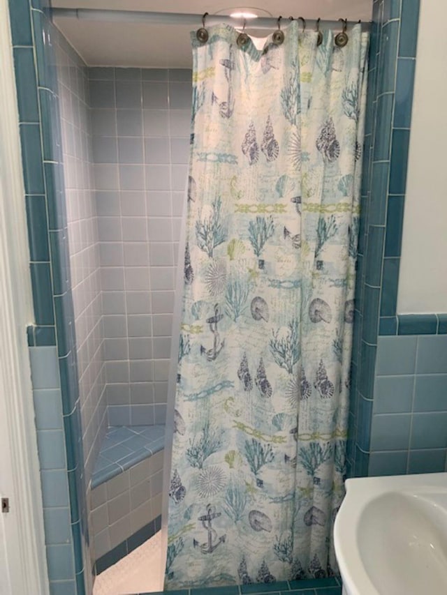 bathroom with tile walls, sink, and a shower with shower curtain