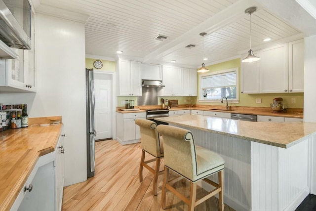 kitchen with wooden counters, sink, a breakfast bar area, and white cabinets