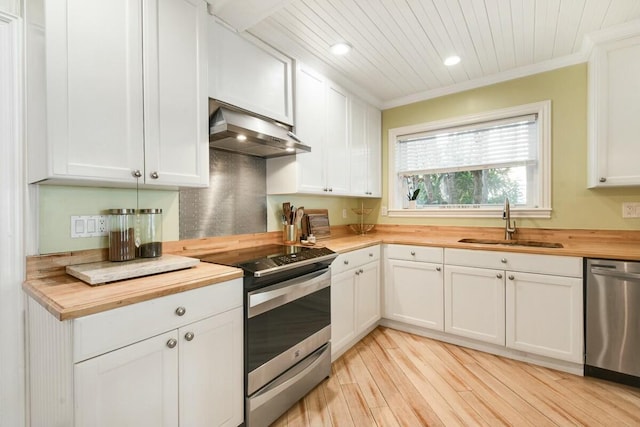 kitchen with appliances with stainless steel finishes, butcher block countertops, white cabinetry, sink, and light hardwood / wood-style floors