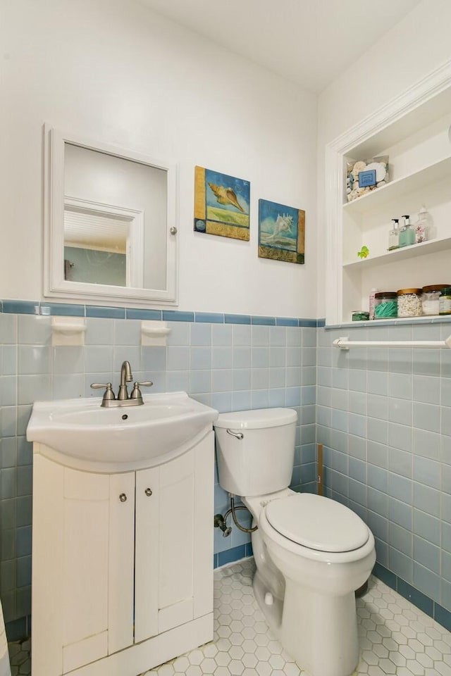 bathroom featuring tile walls, vanity, toilet, tile patterned floors, and built in shelves