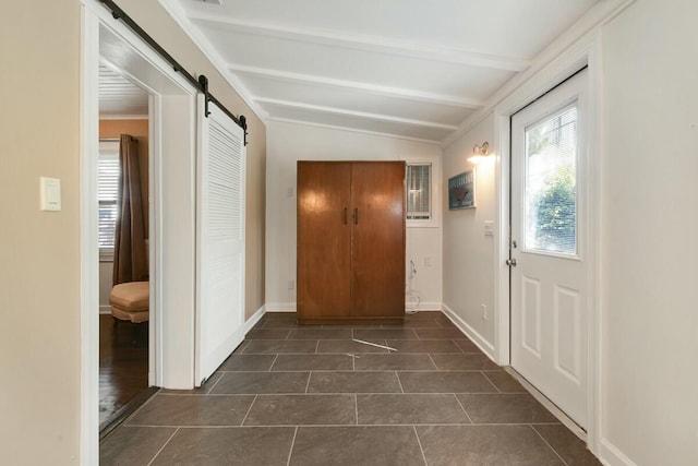 entryway with lofted ceiling with beams, a barn door, and dark tile patterned floors