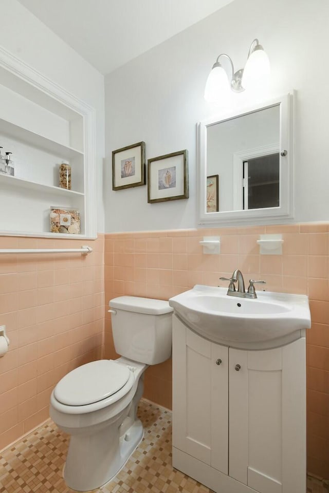 bathroom with vanity, tile walls, and toilet