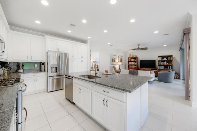 kitchen with appliances with stainless steel finishes, sink, an island with sink, and stone countertops