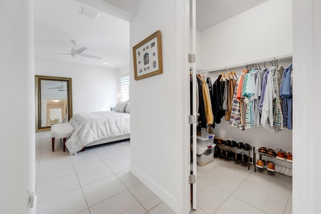 tiled bedroom with ceiling fan and a closet