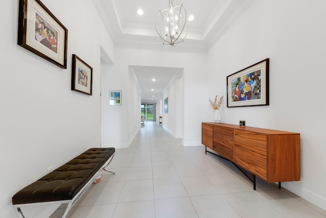 hall with ornamental molding, a chandelier, a raised ceiling, and light tile patterned floors