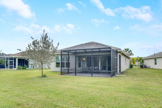 rear view of property featuring glass enclosure, a yard, and a patio