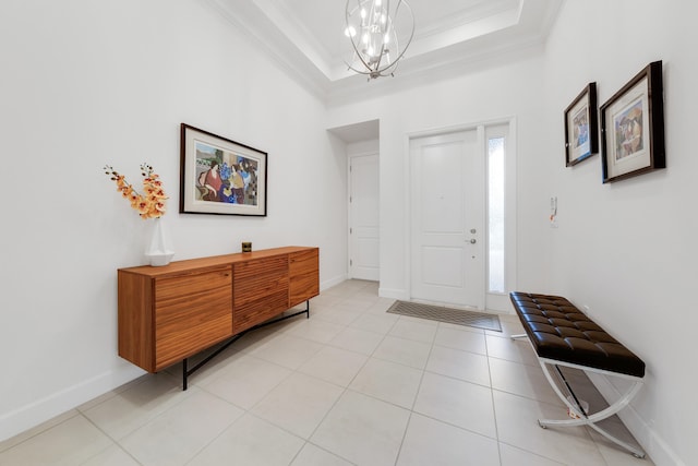 foyer featuring crown molding, a chandelier, a raised ceiling, and light tile patterned floors