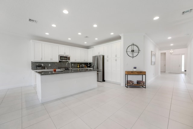 kitchen with stainless steel appliances, dark stone counters, light tile patterned floors, backsplash, and white cabinets