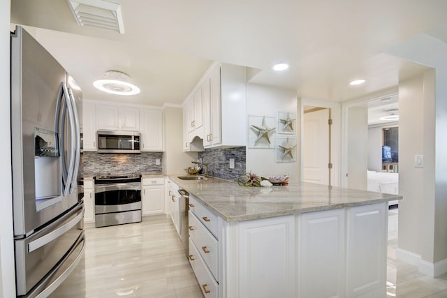 kitchen with tasteful backsplash, sink, white cabinetry, stainless steel appliances, and light stone counters