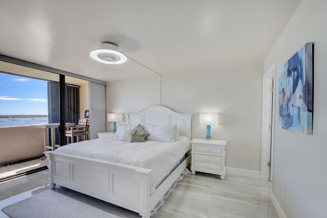 bedroom with a water view, ceiling fan, and light wood-type flooring