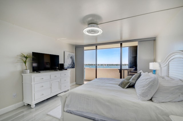 bedroom featuring a wall of windows, access to exterior, and light wood-type flooring