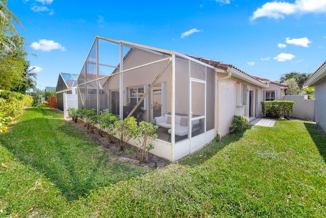 back of property with a sunroom, a yard, and a lanai