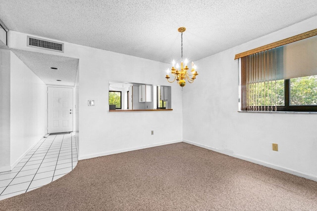 carpeted empty room featuring a chandelier and a textured ceiling