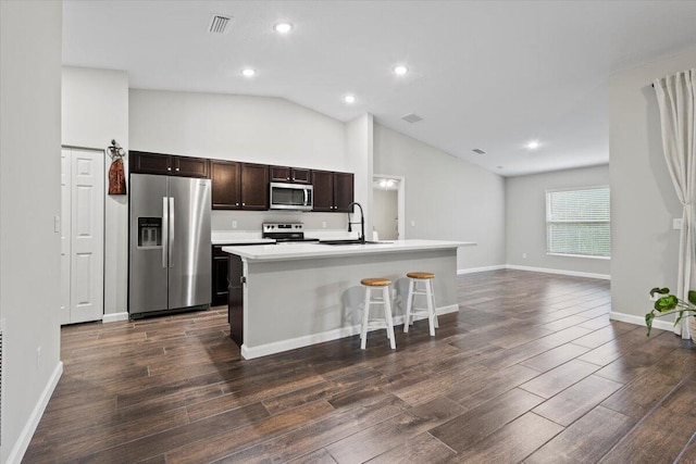 kitchen featuring lofted ceiling, stainless steel appliances, a center island with sink, sink, and a barn door