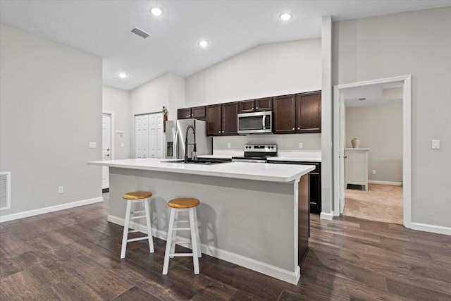 kitchen with lofted ceiling, dark hardwood / wood-style floors, an island with sink, sink, and appliances with stainless steel finishes