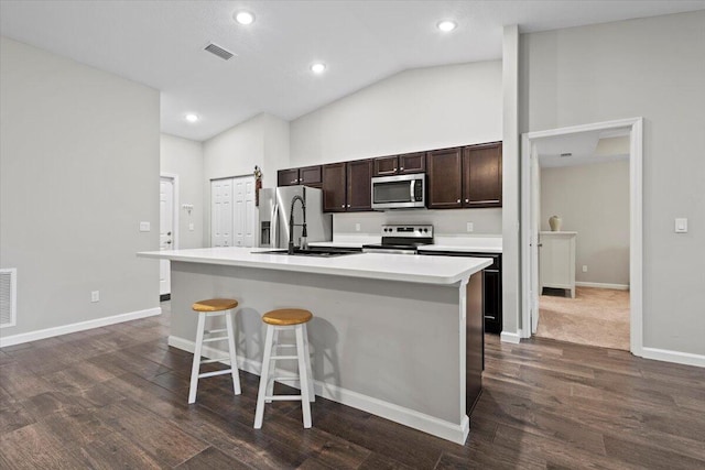 541 SW Nadell Ct, Port Saint Lucie, FL 34953 - kitchen featuring appliances with stainless steel finishes, a center island with sink, dark brown cabinetry, light countertops, and a breakfast bar area