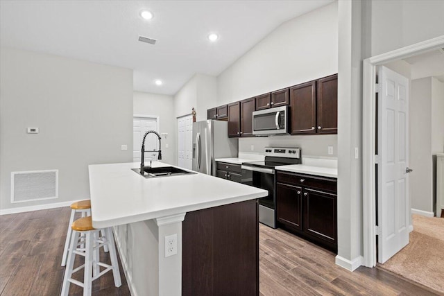 kitchen featuring a breakfast bar, an island with sink, stainless steel appliances, and hardwood / wood-style flooring