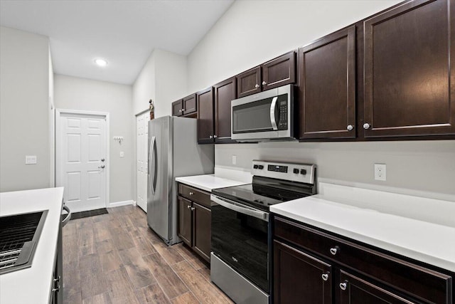 kitchen featuring a barn door, dark brown cabinetry, stainless steel appliances, and dark hardwood / wood-style floors