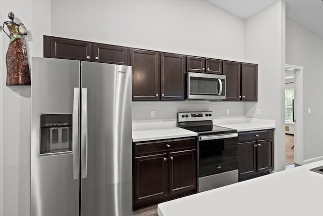 kitchen featuring lofted ceiling, appliances with stainless steel finishes, dark brown cabinetry, and wood-type flooring