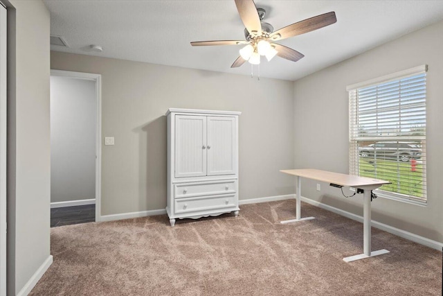 carpeted office space featuring ceiling fan