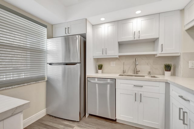 kitchen featuring white cabinets, appliances with stainless steel finishes, light wood-type flooring, and sink