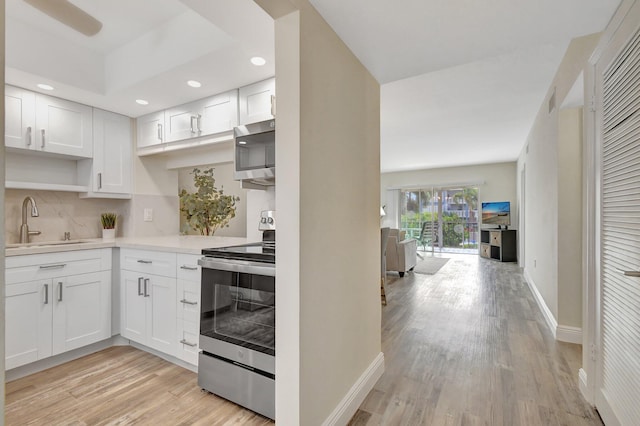 kitchen with white cabinetry, sink, stainless steel appliances, and light hardwood / wood-style floors