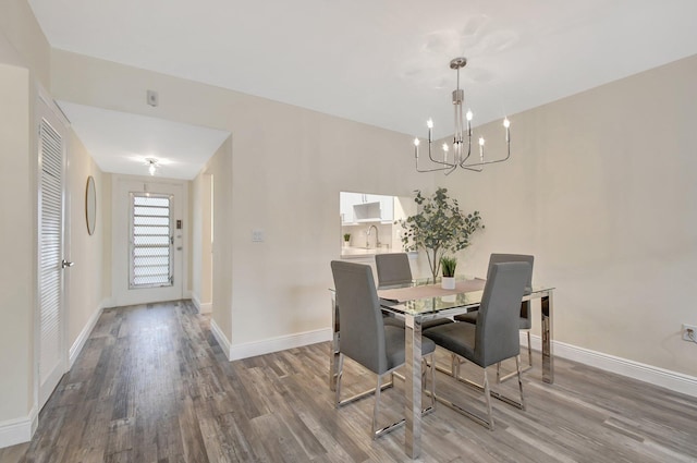 dining space with hardwood / wood-style flooring, sink, and an inviting chandelier