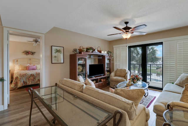 living room with light hardwood / wood-style floors, a textured ceiling, and ceiling fan