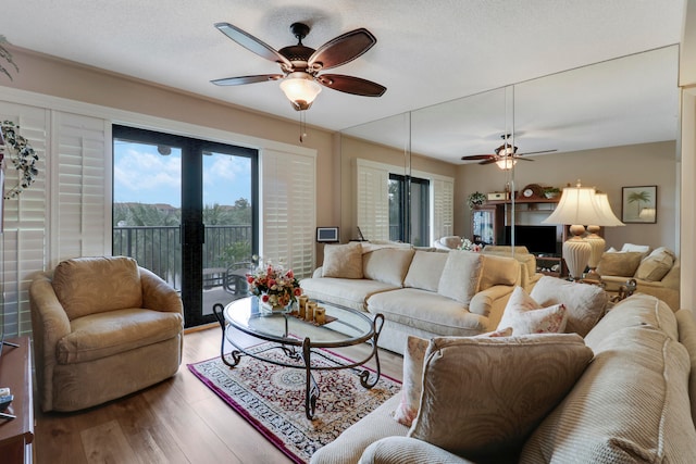 living room featuring wood-type flooring, ceiling fan, and a textured ceiling