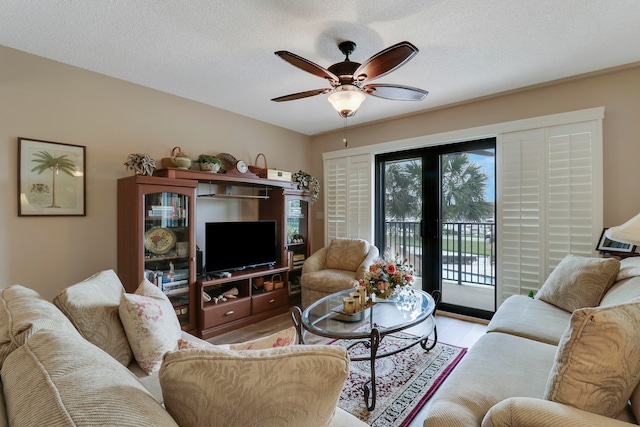 living room featuring ceiling fan, a textured ceiling, and light hardwood / wood-style floors