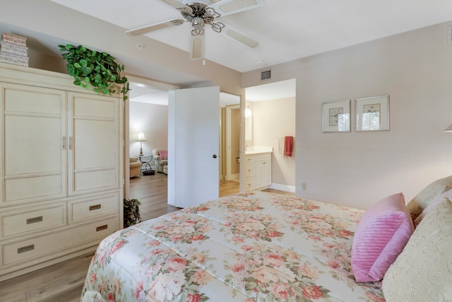 bedroom with ensuite bathroom, light wood-type flooring, and ceiling fan