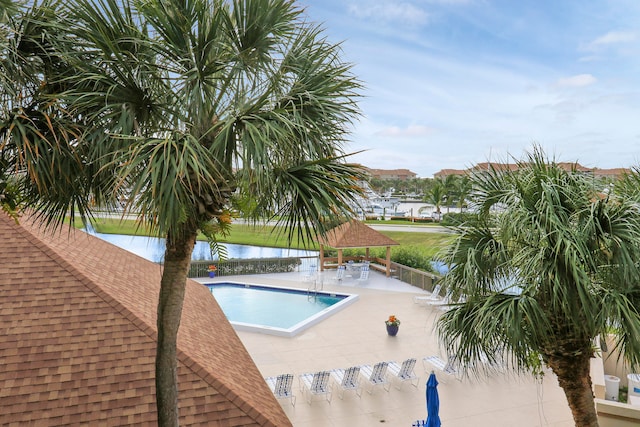 view of swimming pool featuring a patio and a water view