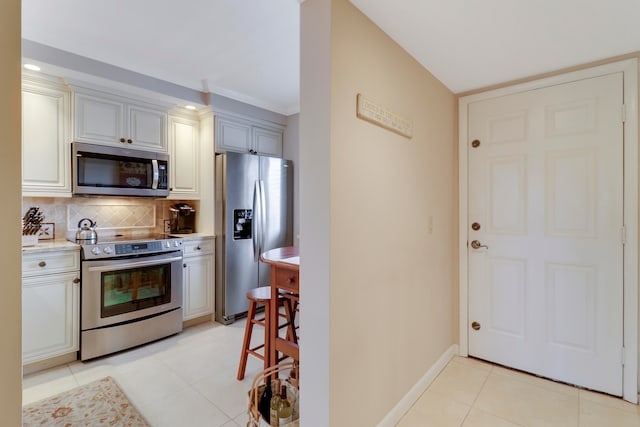 kitchen featuring stainless steel appliances, light tile patterned floors, crown molding, and backsplash