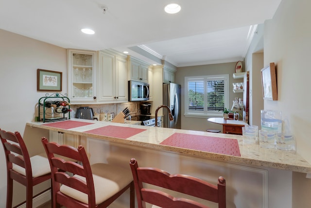 kitchen with stainless steel appliances, a breakfast bar area, kitchen peninsula, and decorative backsplash