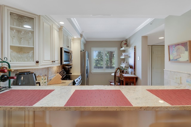 kitchen featuring tasteful backsplash, ornamental molding, appliances with stainless steel finishes, light stone countertops, and sink