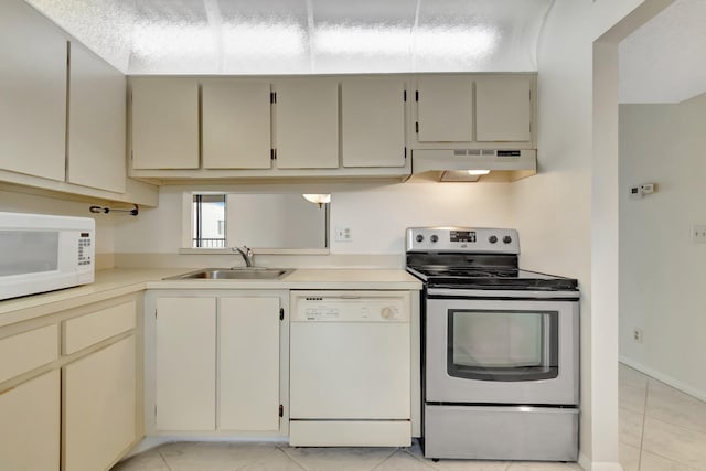 kitchen with light tile patterned flooring, sink, cream cabinetry, and white appliances