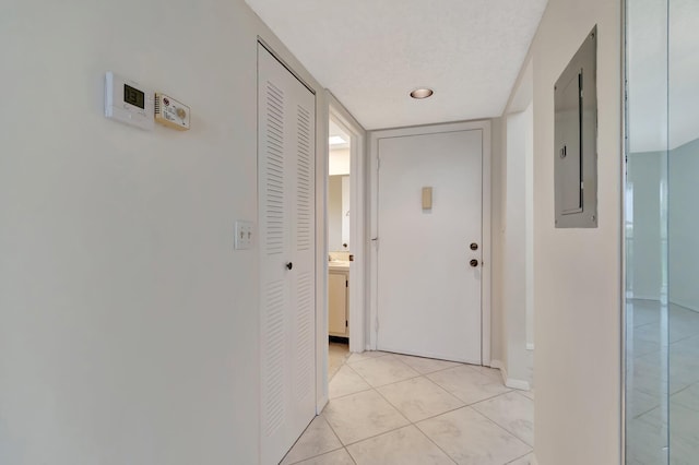 hall with light tile patterned floors and electric panel