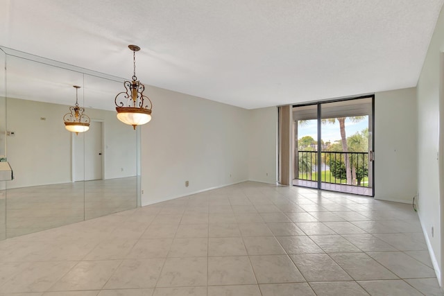 empty room with a textured ceiling, light tile patterned floors, and expansive windows