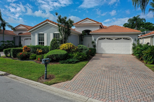 mediterranean / spanish home featuring a garage and a front lawn