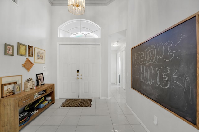 tiled entrance foyer featuring an inviting chandelier, ornamental molding, and a high ceiling