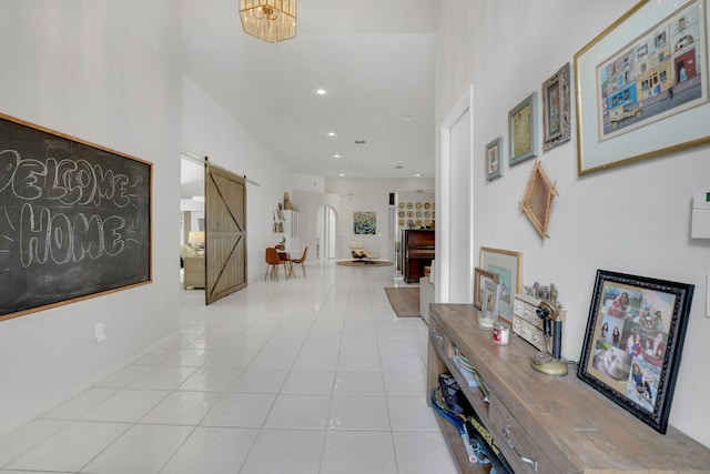 hallway featuring a notable chandelier, light tile patterned floors, and a barn door