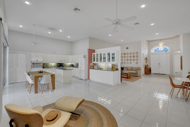 living room featuring ceiling fan, a towering ceiling, and light tile patterned floors