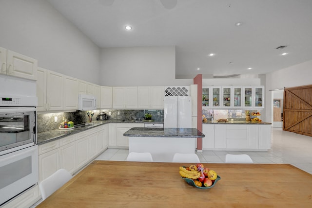 kitchen featuring white cabinetry, a barn door, a kitchen island, and white appliances