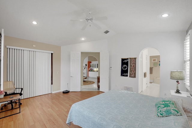 bedroom featuring lofted ceiling, ensuite bath, light wood-type flooring, and ceiling fan