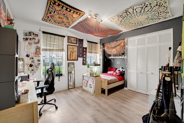 bedroom with a closet, hardwood / wood-style flooring, and track lighting